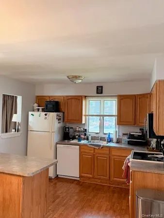 a kitchen with a refrigerator a stove top oven a sink dishwasher and white cabinets with wooden floor