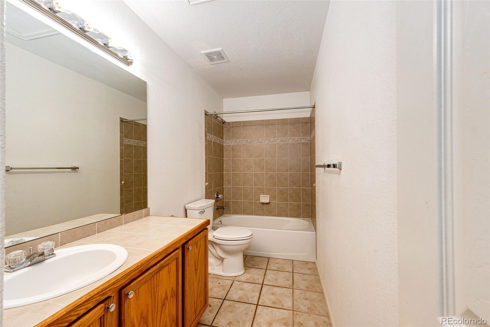 5672 Columbine Ridge Road Elizabeth, CO 80107 - Photo 32 of 50 a bathroom with a granite countertop sink a toilet a mirror and shower