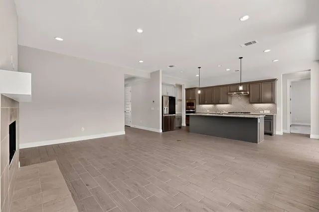 a large kitchen with stainless steel appliances granite countertop a large counter top a oven a sink and a large window