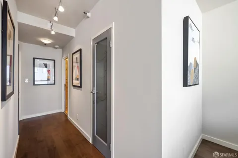 a view of a hallway with wooden floor and a bathroom