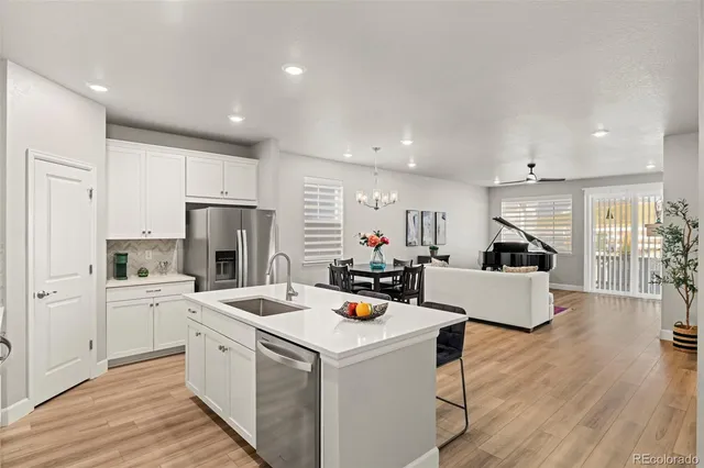 a open kitchen with sink a refrigerator and white cabinets with wooden floor