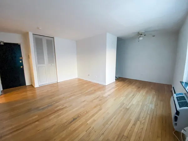 a view of empty room with wooden floor and fan