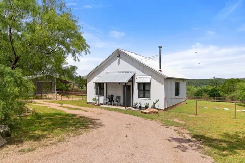 a front view of house with yard and trees in the background