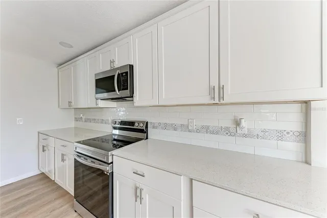 a kitchen with granite countertop white cabinets and stainless steel appliances