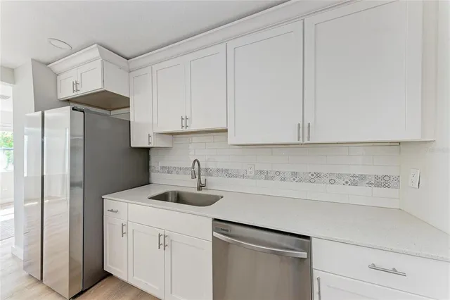a kitchen with stainless steel appliances granite countertop white cabinets and a refrigerator a sink