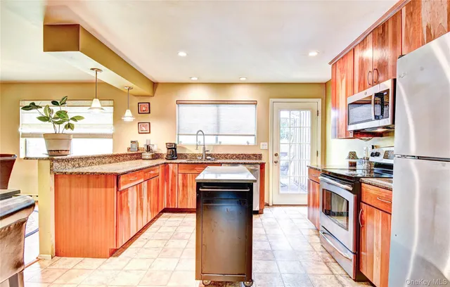 a kitchen with stainless steel appliances granite countertop a stove top oven a sink a dining table and chairs