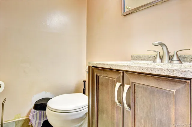 a bathroom with a granite countertop sink and a toilet
