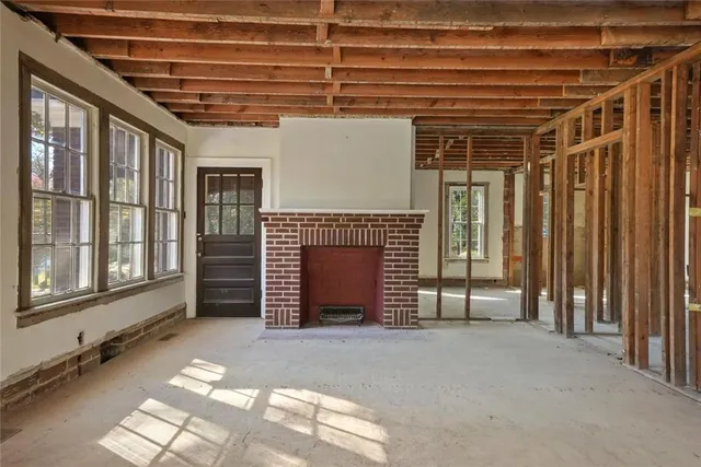 a view of an empty room with a fireplace and windows