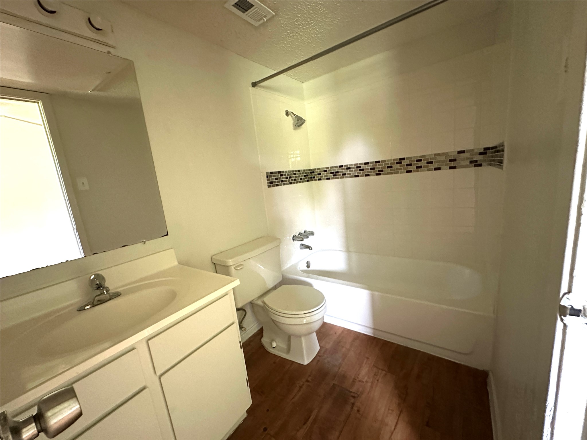 10810 Newmont Road, Unit 7 Austin, TX 78758 - Photo 11 of 13 Bathroom featuring a white vanity with an integrated sink, a mirror, and a bathtub with a tiled shower surround