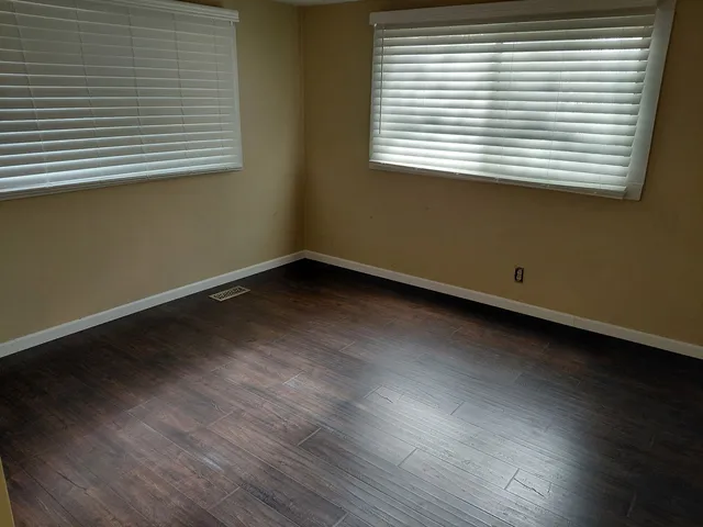 an empty room with wooden floor and a window