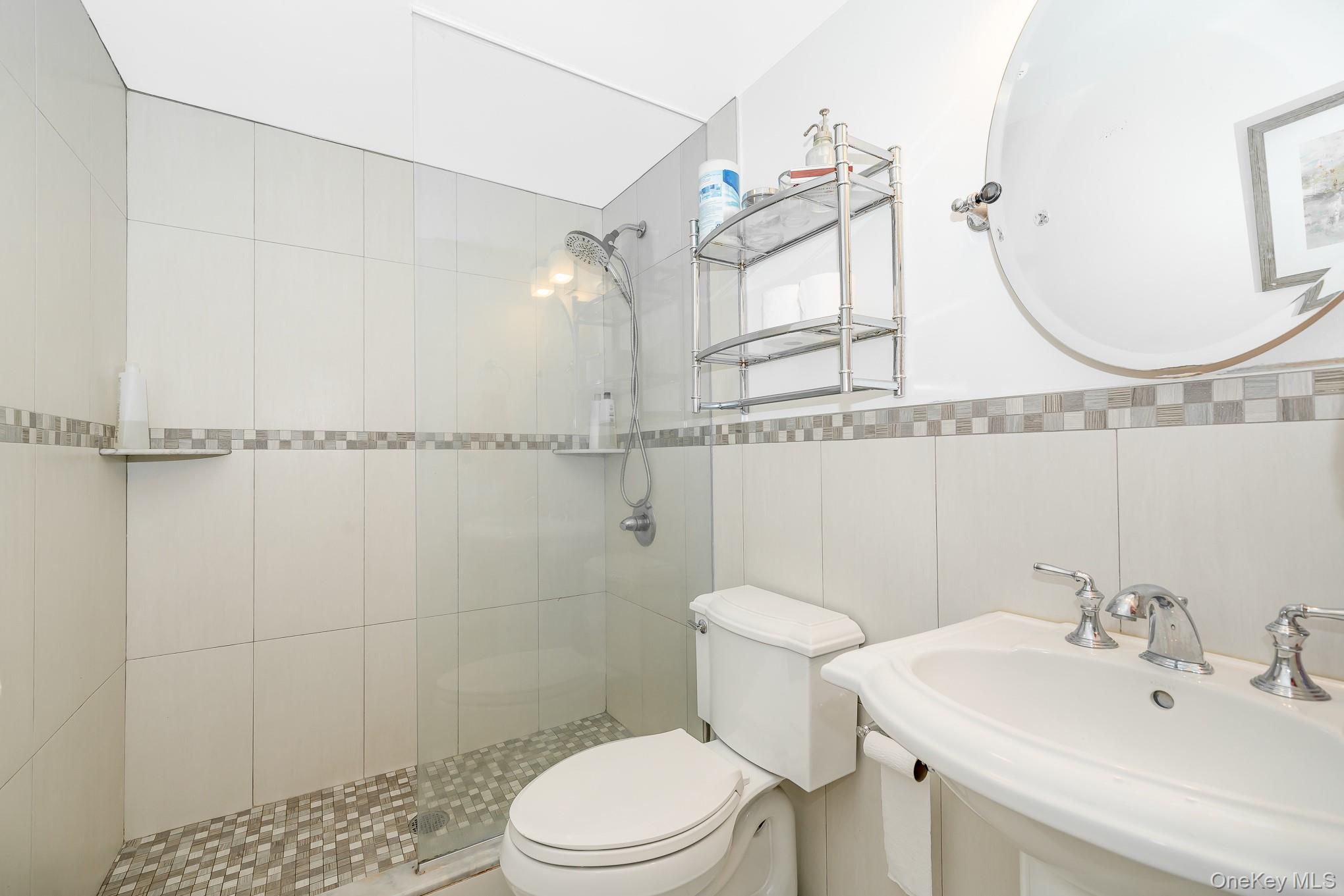 136 Wardwell Road Mineola, NY 11501 - Photo 12 of 25 Full bath featuring a sink, toilet, tiled shower, and tile walls