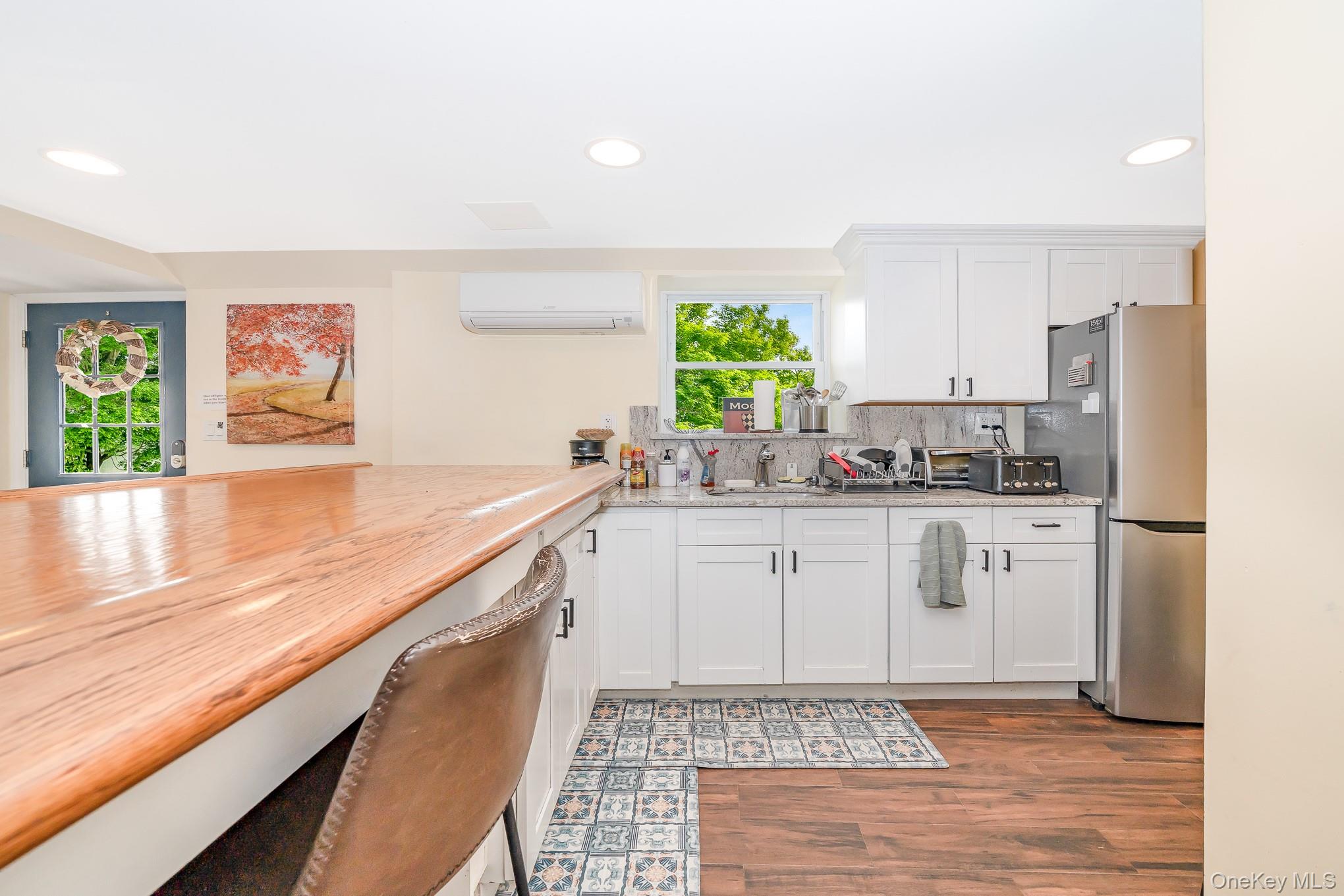 136 Wardwell Road Mineola, NY 11501 - Photo 15 of 25 Kitchen featuring a wall mounted air conditioner, freestanding refrigerator, recessed lighting, wood finished floors, and white cabinets