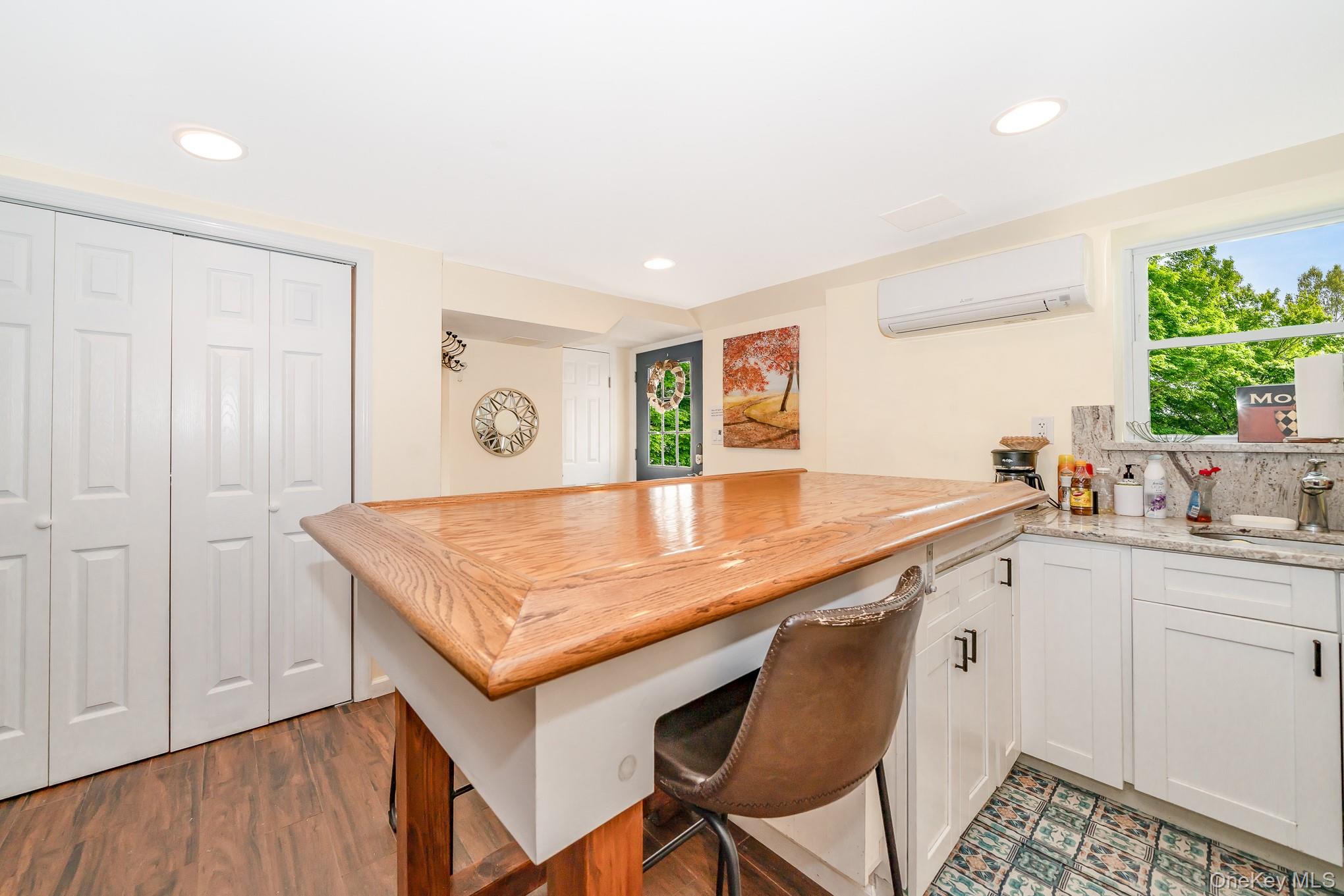 136 Wardwell Road Mineola, NY 11501 - Photo 16 of 25 Kitchen featuring a wall mounted AC, a peninsula, recessed lighting, light stone counters, and white cabinetry