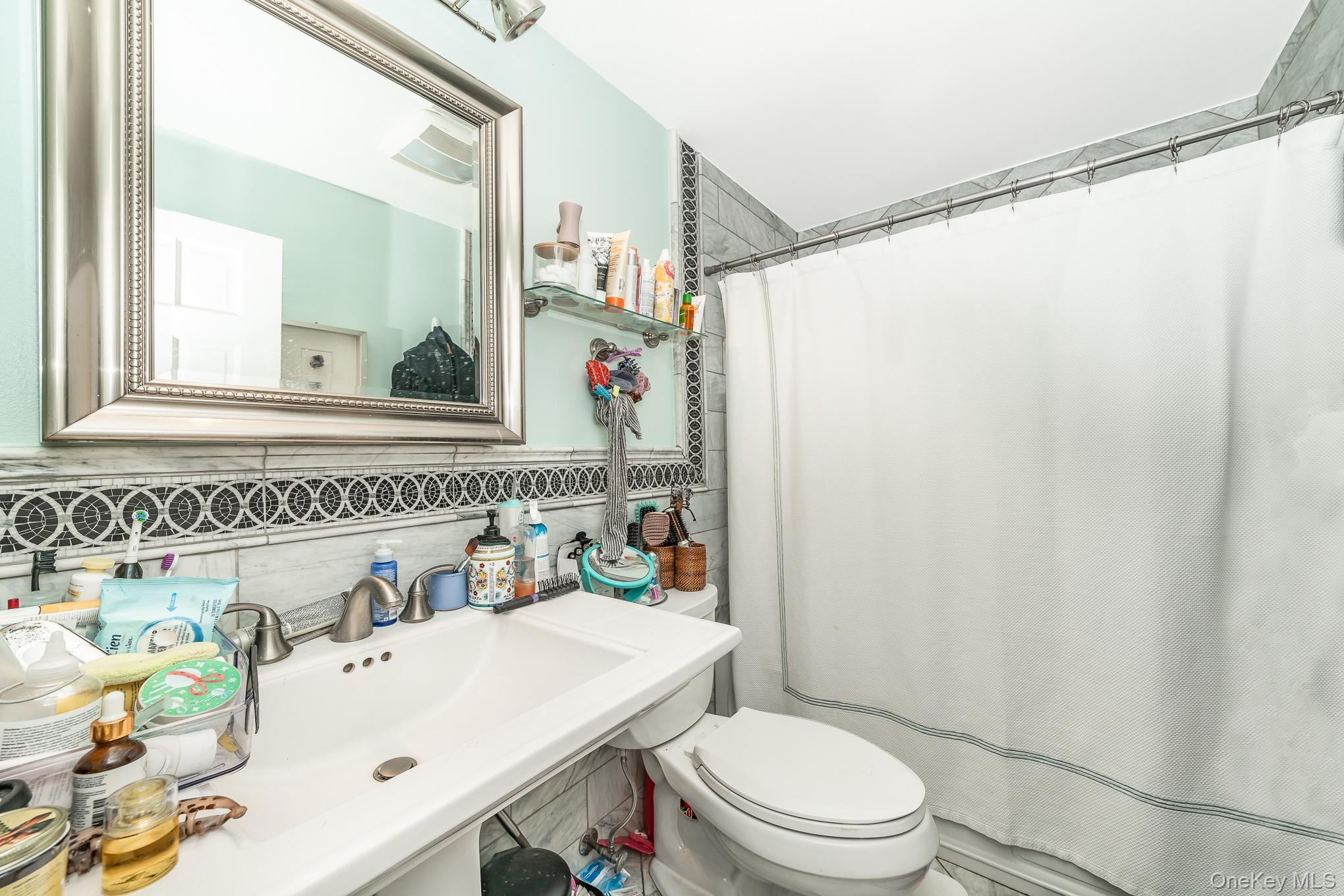 136 Wardwell Road Mineola, NY 11501 - Photo 19 of 25 Bathroom with toilet, a shower with curtain, and decorative backsplash