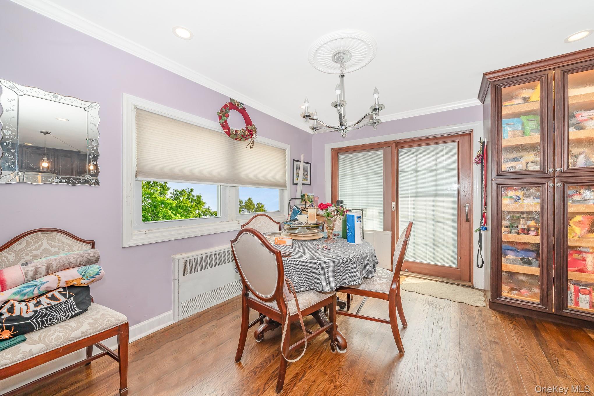 136 Wardwell Road Mineola, NY 11501 - Photo 20 of 25 Dining area featuring radiator, a chandelier, ornamental molding, wood finished floors, and baseboards