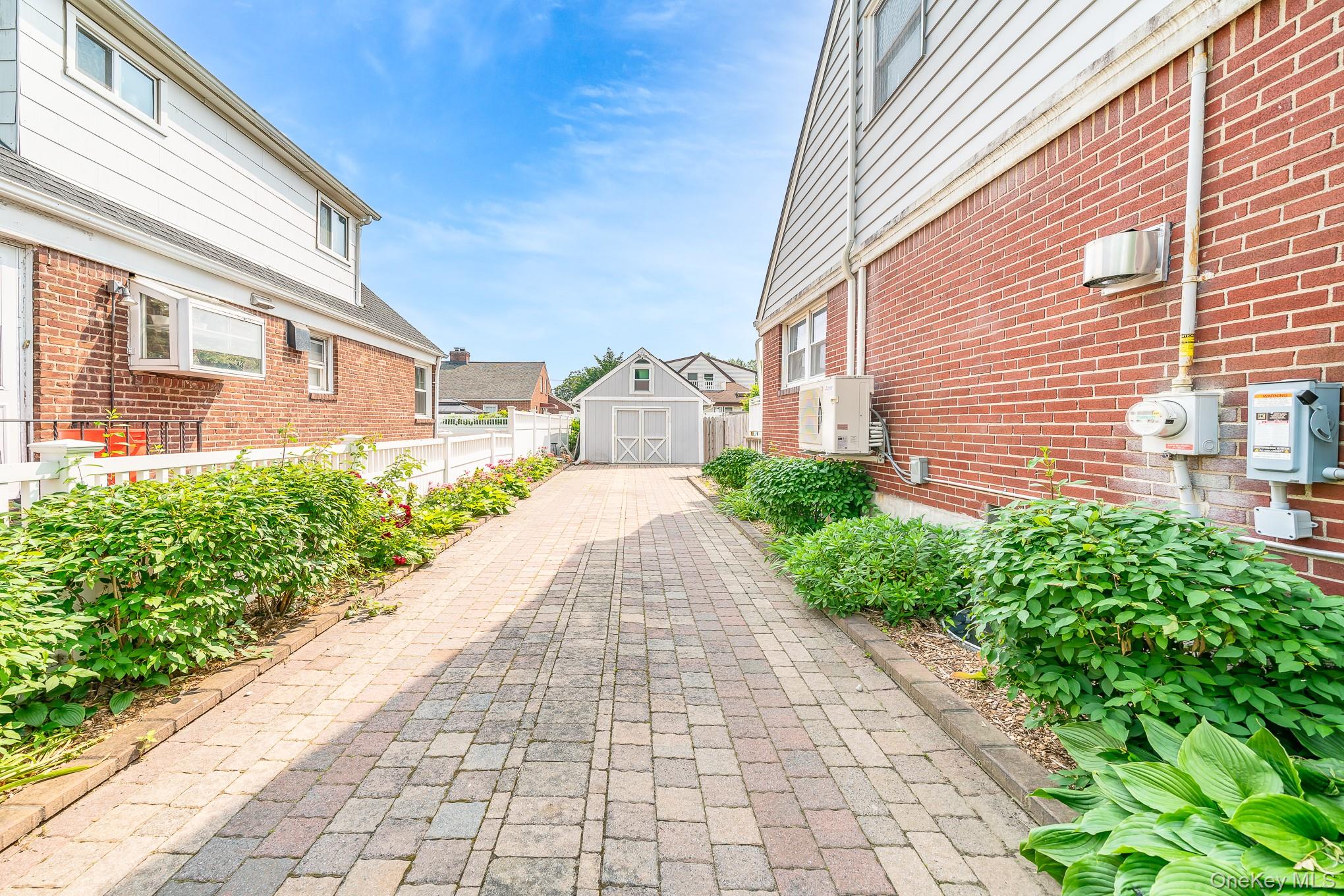 136 Wardwell Road Mineola, NY 11501 - Photo 3 of 25 View of side of property featuring brick siding, a residential view, and a wall mounted AC