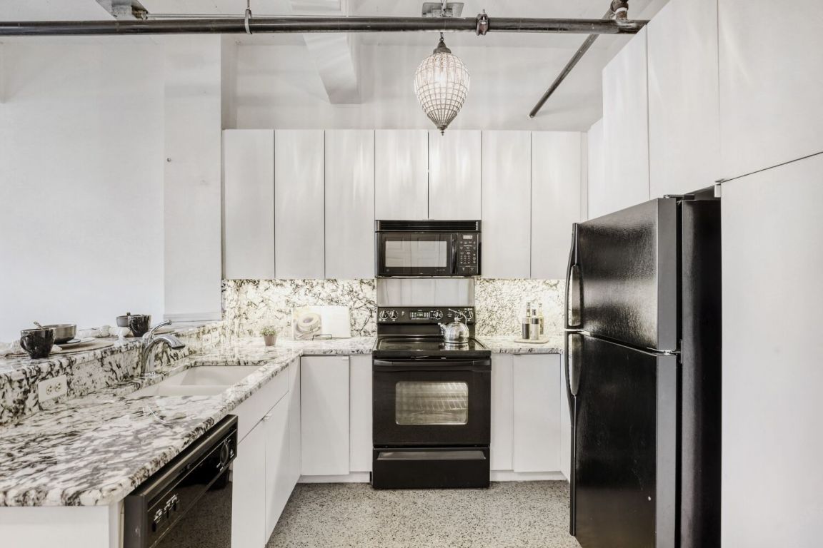 710 Colorado Street, Unit 4G Austin, TX 78701 - Photo 10 of 39 The kitchen is fully equipped with premium granite countertops and backsplash that contrast cleanly with sleek white contemporary cabinetry.