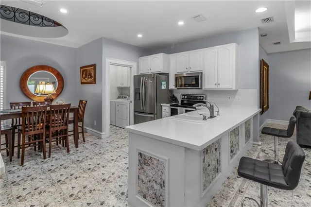 a kitchen with stainless steel appliances a dining table chairs stove refrigerator and microwave