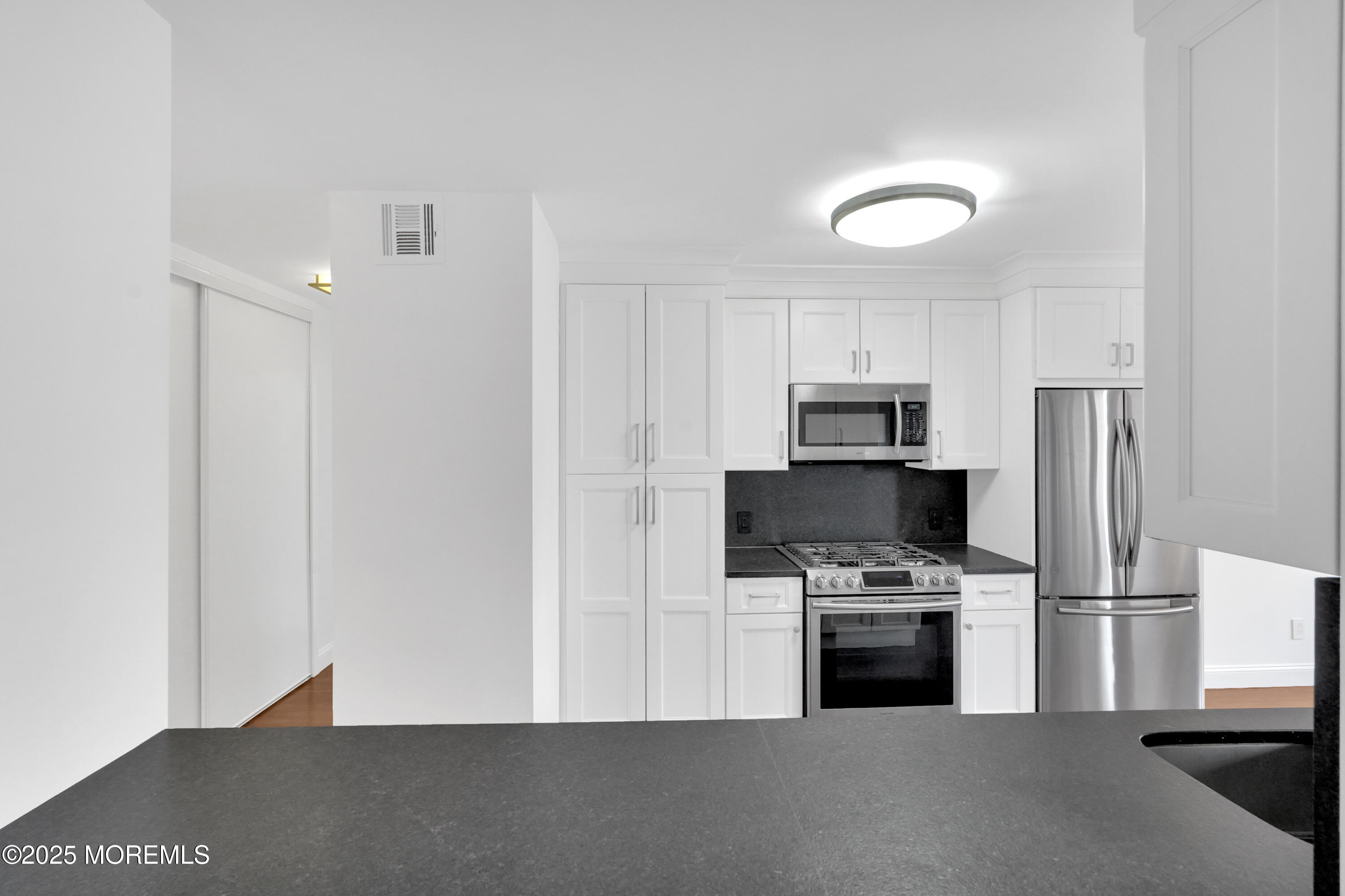 28 Riverside Avenue, Unit 5J Red Bank, NJ 07701 - Photo 4 of 35 a kitchen with stainless steel appliances a refrigerator a stove a microwave and a refrigerator