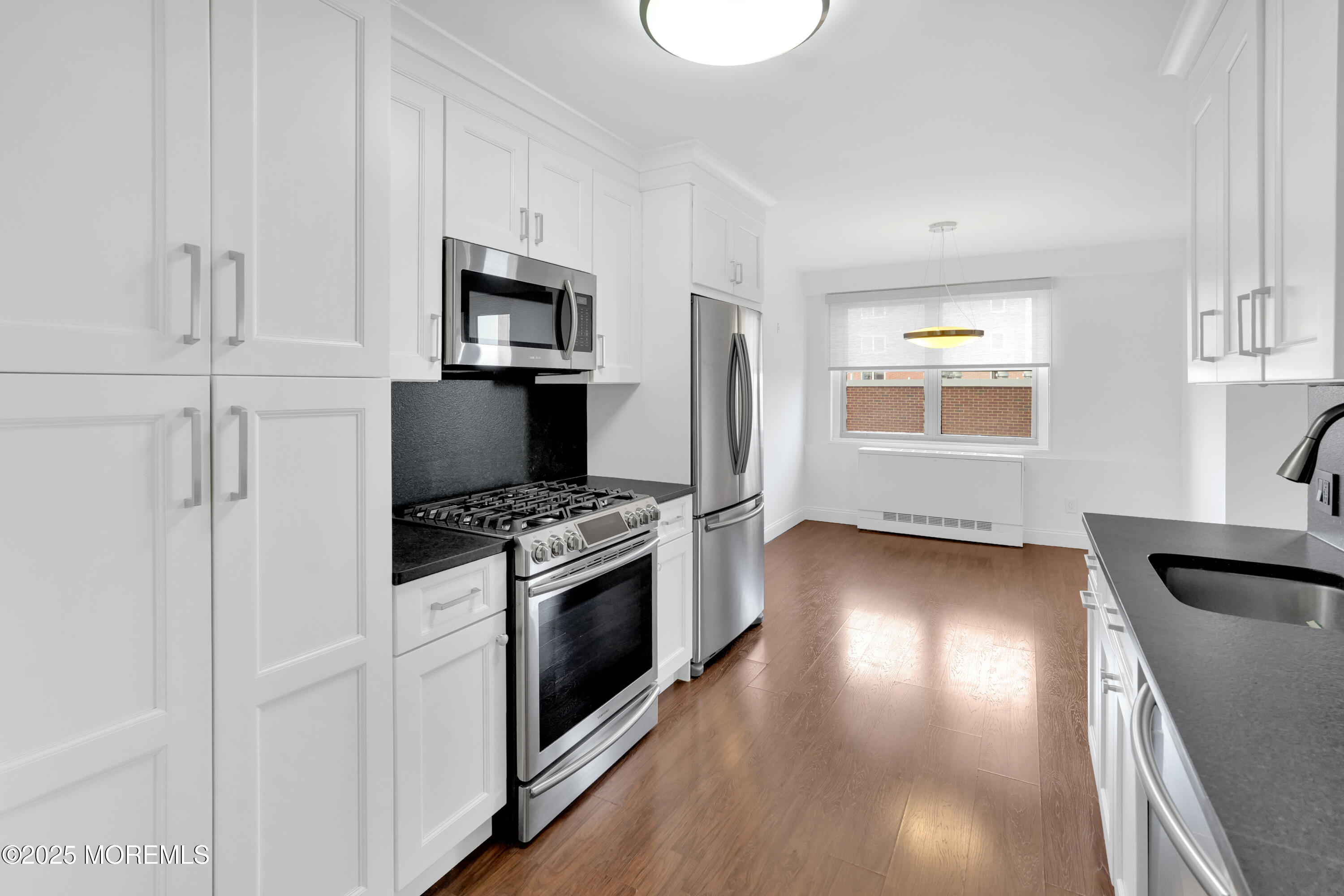 28 Riverside Avenue, Unit 5J Red Bank, NJ 07701 - Photo 9 of 35 a kitchen with a stove a microwave and a hard wood floor
