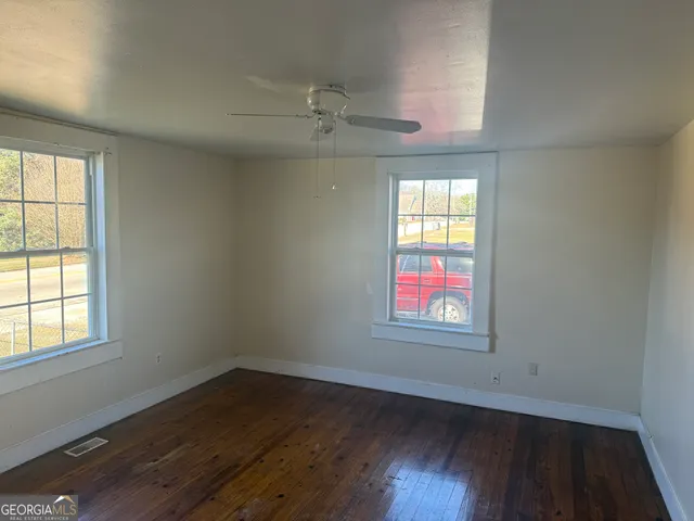 an empty room with wooden floor and windows