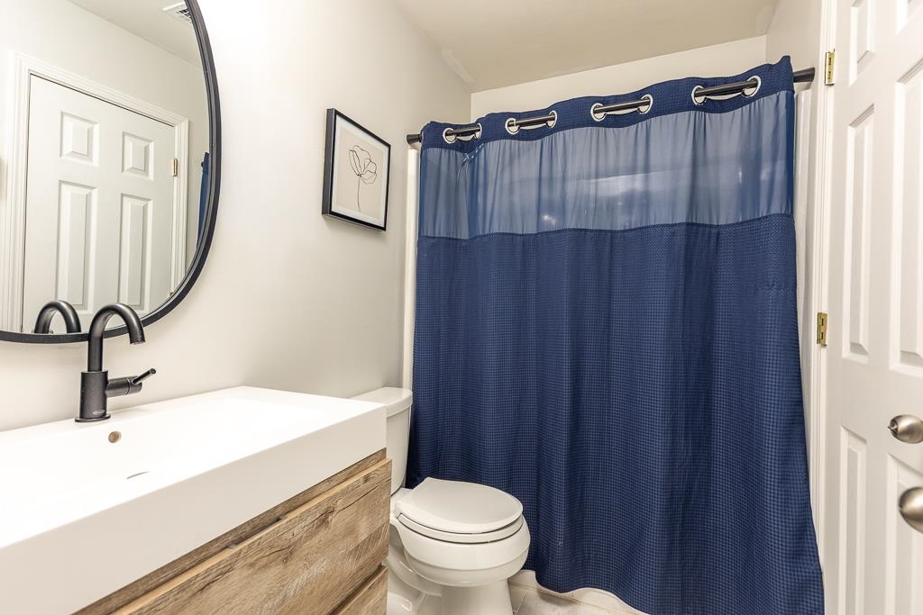1290 Isle Pointe Drive Memphis, TN 38103 - Photo 20 of 30 a bathroom with a sink a toilet a mirror and shower curtain