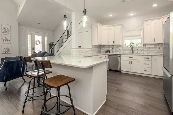 a large kitchen with cabinets chairs and wooden floor