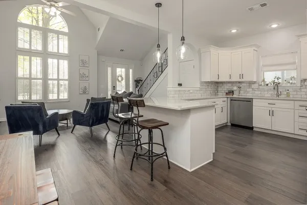 a open kitchen with granite countertop a stove a sink a island and chairs with wooden floor