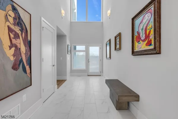 a hallway with painting on the wall and a large mirror