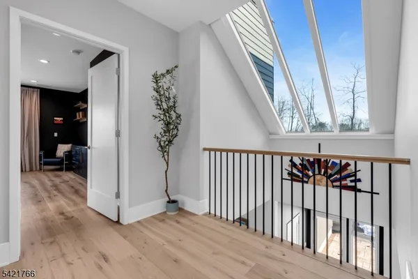 a view of a hallway to a livingroom with wooden floor and stairs