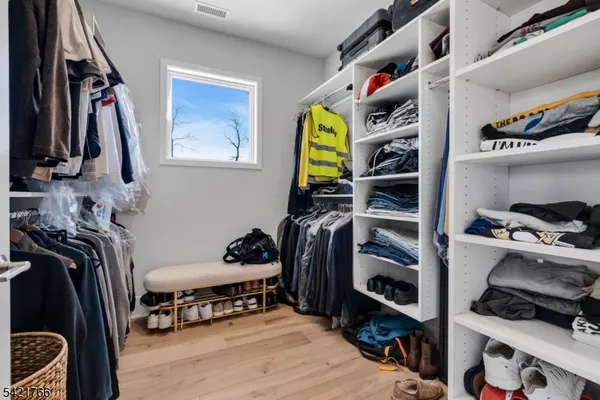 a view of walk in closet with clothes and shoes