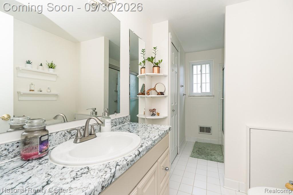 67976 Van Dyke Road, Unit 15 Washington, MI 48095 - Photo 21 of 35 Bathroom featuring a vanity with an integrated sink, a speckled countertop, a large wall mirror, and white tiled flooring
