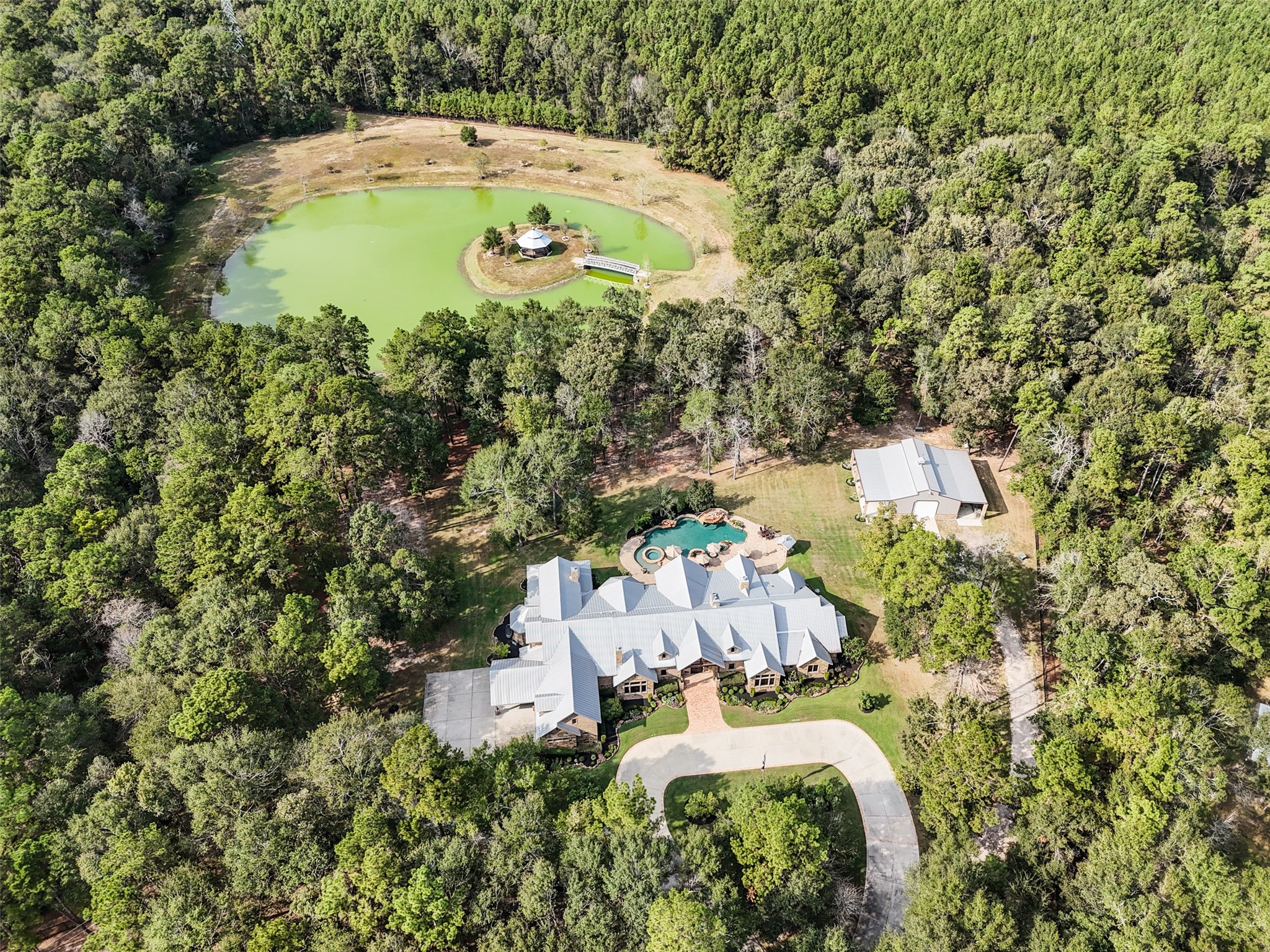 This exquisite property features 14.5 natural wooded acreage, a 3 acre pond with 3 acres of cleared land surrounding it, an almost 9,000 square foot home constructed in 2014, a gazebo, barn, playground and 50,000 gallon pool! Buyers may build an additional main home, guest home, and barn/shop/outbuilding on the 14.5-acre tract! Buyers may also extend the existing main home (if desired) on the 10-acre tract, and build a guest house on that portion of the property! So many possibilities!