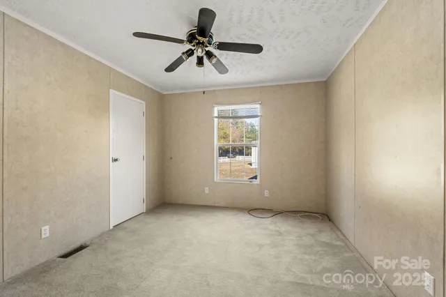 an empty room with a ceiling fan and windows