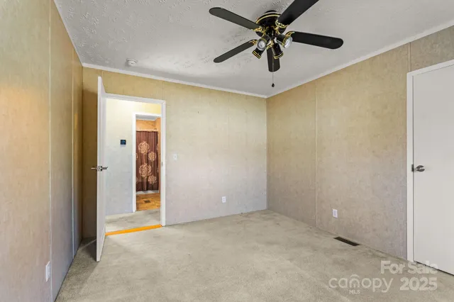 an empty room with a ceiling fan and carpet