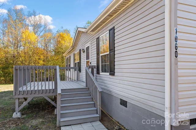a view of a house with a small deck and a backyard