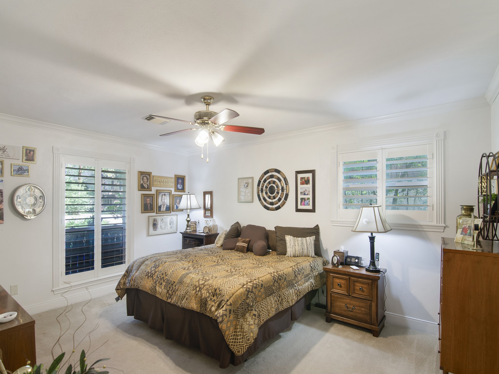 532 Raleigh Drive Conroe, TX 77302 - Photo 11 of 40 Relax in the first-floor primary bedroom featuring soft carpeting, ceiling fan and window shutters, all in neutral colors.