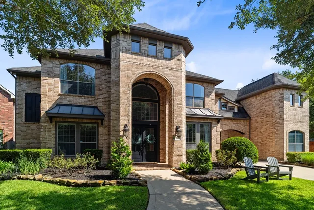 a view of house with a yard and a large tree