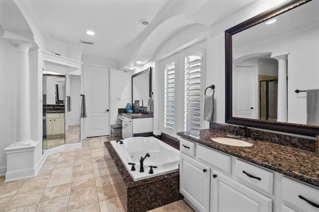 a bathroom with a granite countertop tub a sink and a window