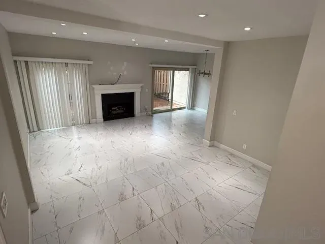 a view of an empty room with glass door and wooden floor