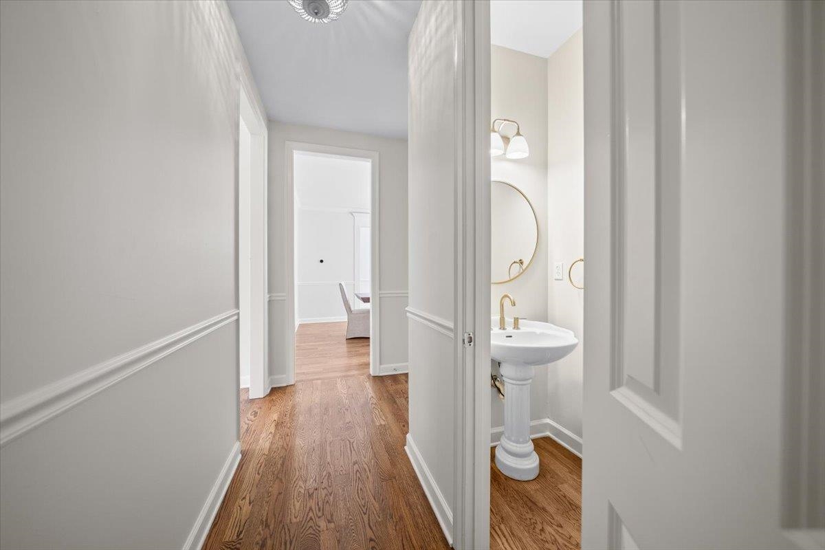 1876 Liles Lane Collierville, TN 38017 - Photo 23 of 36 Powder room featuring a pedestal sink with a gold-finish faucet, a circular mirror, and a two-light vanity fixture