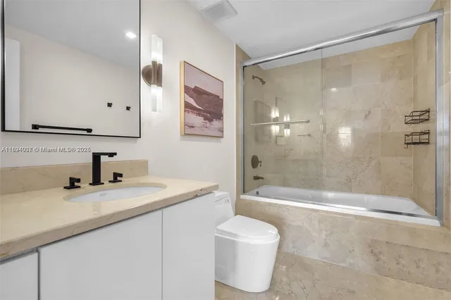 a bathroom with a granite countertop sink a toilet a mirror and shower