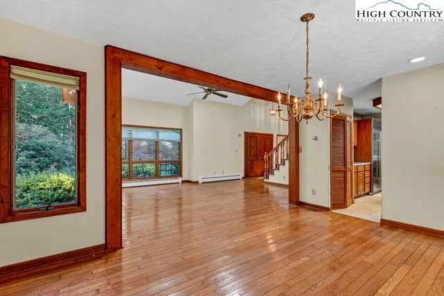 a view of an empty room with wooden floor a fireplace and a window
