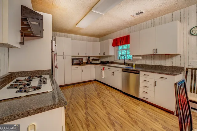a kitchen with granite countertop a sink cabinets stainless steel appliances and a counter top space