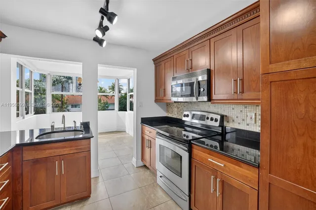 a kitchen with stainless steel appliances granite countertop a refrigerator a stove and a sink