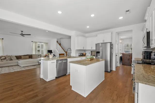 a large white kitchen with a refrigerator a stove a sink dishwasher a oven and a dining table with wooden floor