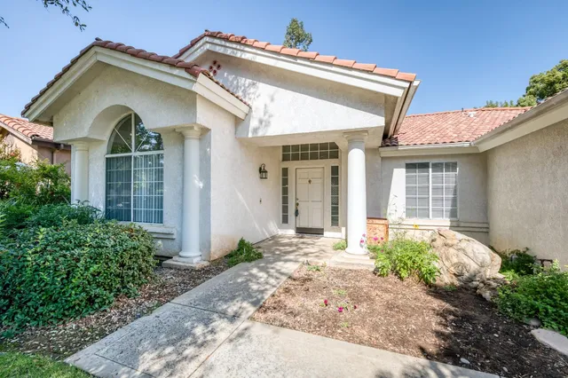 a view of a white house with a large window and potted plants