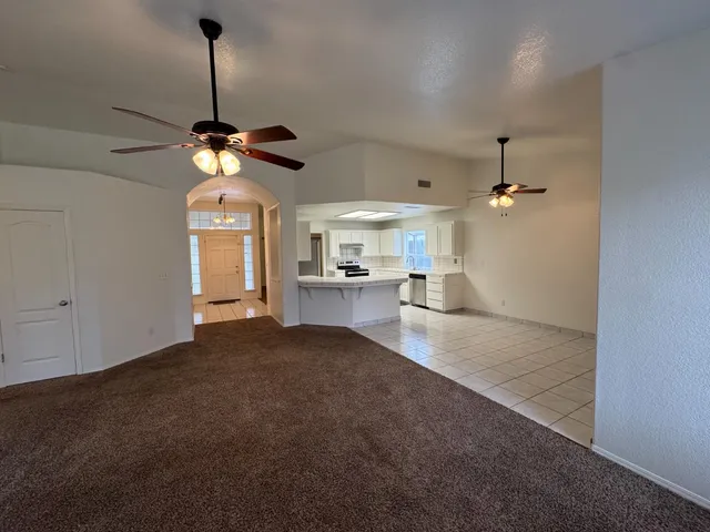a view of living room with kitchen island stainless steel appliances furniture a fireplace and a chandelier