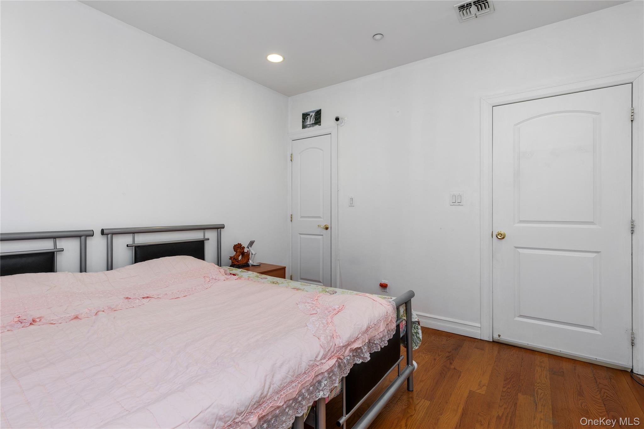 10716 37th Avenue, Unit 3B Queens, NY 11368 - Photo 11 of 19 a bedroom with a bed and wooden floor