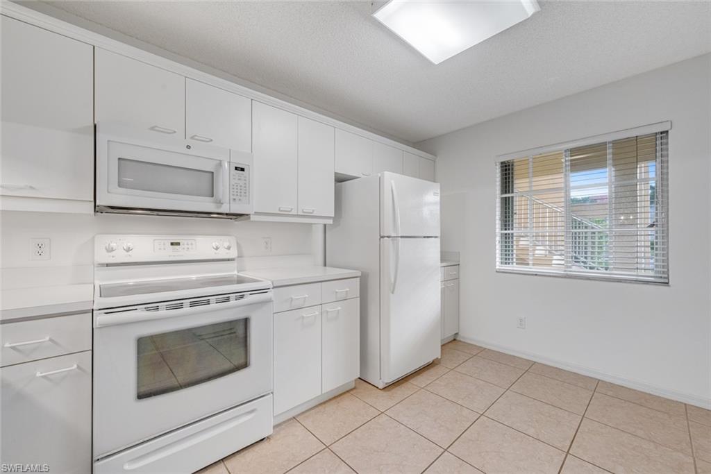 7761 Jewel Lane, Unit 103 Naples, FL 34109 - Photo 11 of 26 a kitchen with white cabinets and white appliances